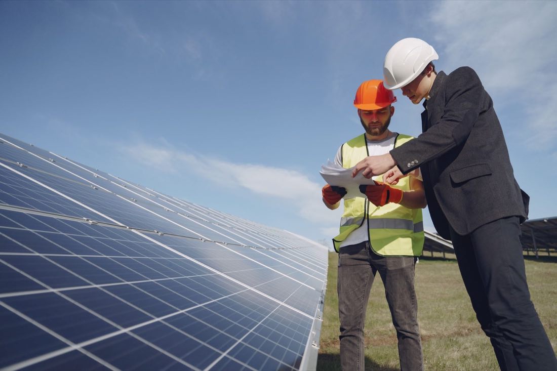 Zwei Fachleute prüfen Unterlagen in einem Solarpark